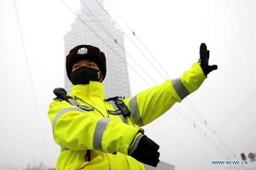 A traffic policewoman with a mask directs the traffic in Jinan, capital of east China's Shandong Province, Jan. 30, 2013. The local traffic policemen used masks to protect their health in hazy days.(Xinhua/Xu Suhui) 