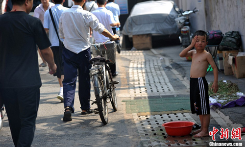A boy washes himself in a Huashiying alley as people walk by. With little running water available, bathing proves a headache for most residents. Photo: Jin Shuo/chinanews.com 
