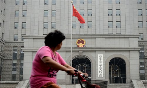 A woman rides a bicycle in front of a courthouse during the sentencing of China's former railways minister Liu Zhijun in Beijing on Monday. Photo: AFP