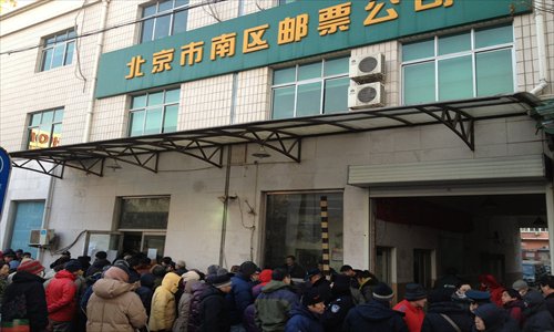 Despite the cold, a large number of stamp collectors who are eager to buy the first edition of stamps for the Year of the Snake mob a post office in Xicheng district Saturday morning. Photo: IC