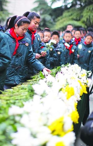 Children lay flowers in front of the Mass Grave Site before entering the memorial hall. Photo: Cai Xianmin/GT
