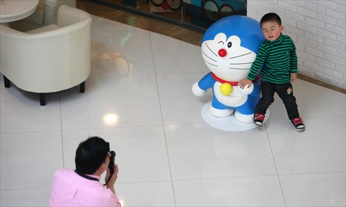 A man snaps a shot of a little boy with a Doraemon figure Saturday. Photo: Cai Xianmin/GT
