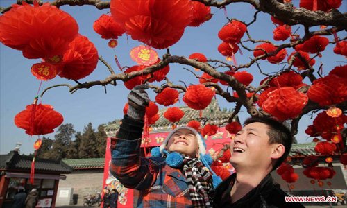 People look at red lanterns hung on a tree outside the south gate of Ditan Park in Beijing, capital of China, Feb. 8, 2013. The Spring Festival, the most important occasion for the family reunion for the Chinese people, falls on the first day of the first month of the traditional Chinese lunar calendar, or Feb. 10 this year. Photo: Xinhua