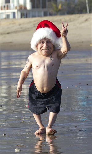 Verne Troyer, at 81 centimeters in height, wears a Santa hat while filming for German TV commercial on a Malibu beach in Los Angeles, California, on Friday. Photo: IC