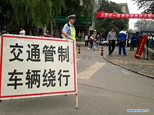 A traffic police helps take traffic control measures to serve the national college entrance exam at the Affiliated High School of Peking University in Beijing, capital of China, June 7, 2013. Some 9.12 million applicants are expected to sit this year's college entrance exam on June 7 and 8. (Xinhua/Li Xin)