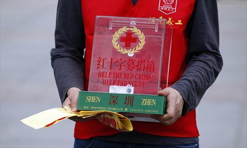 A volunteer from the Shenzhen branch of the Red Cross Society of China holding a nearly empty donation box asks pedestrians to donate money for people in the quake-hit zones in Sichuan Province on Sunday. Photo: CFP
