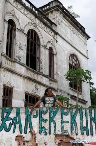 An indigenous man stands behind a wall around the old Indian Museum in Rio de Janeiro, Brazil, Jan. 16, 2013. The government of Rio de Janeiro plans to tear down an old Indian museum beside Maracana Stadium to build parking lot and shopping center here for the upcoming Brazil 2014 FIFA World Cup. The plan met with protest from the indigenous groups. Now Indians from 17 tribes around Brazil settle down in the old building, appealing for the protection of the century-old museum, the oldest Indian museum in Latin America. They hope the government could help renovate it and make part of it a college for indigenous Indians. (Xinhua/Weng Xinyang) 