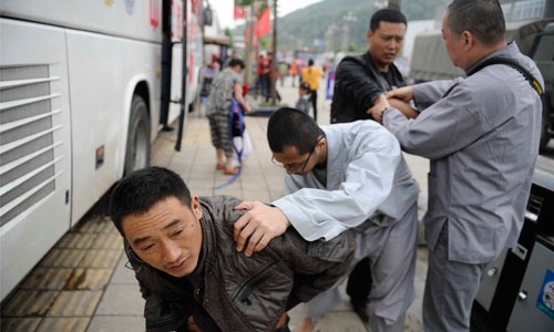 Two monks examine men who suffered injuries during the Ya’an earthquake on April 25. Photo: Li Hao/GT