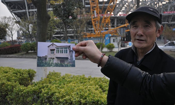 Teng Xiaoming and his daughter Teng Xueqin (outside) show a picture of their former home across the street from the center. Photo: Liu Linlin/GT 