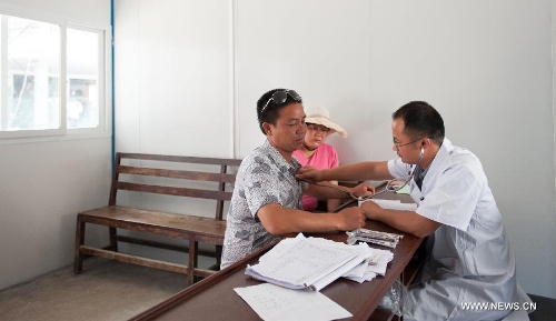 A resident receives medical checkup in a temporarily-erected prefabricated house at the People's Hospital in Lushan County, southwest China's Sichuan Province, May 12, 2013. Eight prefabricated houses have been built here to provide medical services to residents. The county was jolted by a 7.0-magnitude earthquake on April 20. (Xinhua/Li Hualiang) 