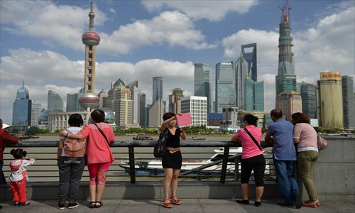 A female tourist (center) uses a mobile device to take photos on the Bund in Shanghai on Wednesday, where China will officially open its first free trade zone later this month in an ambitious effort to transform its commercial center into a global hub. Photo: AFP