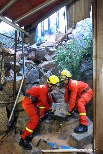 Rescuers try to carry away a rock at the site of a landslide in Xiamen, southeast China's Fujian Province, May 16, 2013. Torrential rainfall triggered a landslide at the Qianpu Flea Market in Xiamen early May 16, causing one adult and two children dead. (Xinhua/Zeng Demeng)&nbsp; 