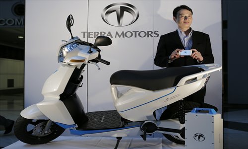 Terra Motors Co CEO Toru Tokushige holding an iPhone poses with the newly launched electronic scooter A4000i during a news conference in Tokyo, Wednesday. The firm unveiled an electric motorcycle that can connect with Apple's iPhone for data transfers. Terra will begin production in Vietnam at the end of this year, with a sales target of 100,000 units  by the end of 2015. Photo: IC