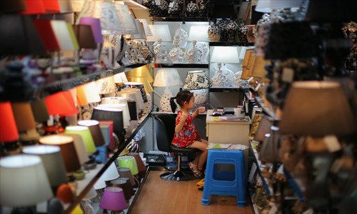 A little girl sits in a lamp shop at China Commodity City, Yiwu of Zhejiang Province. At the end of May, the Chinese trade hub of Yiwu plans to expand a pilot scheme which allows cross-border yuan settlement, the Shanghai Securities News reported Friday, as a way to help local traders hedge exchange rate fluctuation risks. Photo: CFP 