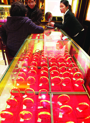 Consumers choose gold products at a gold shop in Yichang, Central China's Hubei Province Thursday. As mid-February's Spring Festival draws near, gold consumption and investment have become popular among Chinese consumers. Boosted by quantitative easing policies carried out by nations such as Japan and the US, gold prices rose in recent days to around $1,700 per ounce. Photo: CFP