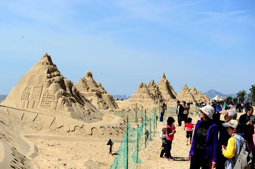 People walk past sand sculptures along the beach in Nanhai New District in Wendeng City, east China's Shandong Province, April 29, 2013. The 2,500-meter-long sand sculpture group attracted many tourists on Monday, the first day of the three-day Labor Day holiday. (Xinhua/Guo Xulei) 