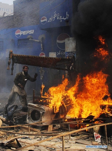 A Pakistani demonstrator torches belongings of Christian families during a protest in a Christian neighborhood in Badami Bagh area of eastern Pakistan's Lahore on March 9, 2013. Hundreds of angry protestors on Saturday set ablaze more than 100 houses of Pakistani Christians over a blasphemy row in the eastern city of Lahore, local media reported. Over 3,000 Muslim protestors turned violent over derogatory remarks allegedly made by a young Christian against Prophet Mohammed in a Christian neighborhood in Badami Bagh area. (Xinhua Photo/Sajjad) 