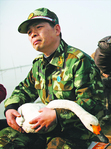 Xu Yaping holds a goose in his arms as he patrols the waters of Dongting Lake with his volunteer crew in Yueyang, Hunan Province. Photo: IC