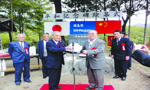 Yasuyuki Sato (front left) presents a gift to Masanosuke Inomata, head of a monument founding committee in Aizuwakamatsu, Fukushima, at an unveiling ceremony of a marker commemorating the Sino-Japan friendship in 2011. Photo: Courtesy of the Consulate-General of the People's Republic of China in Niigata