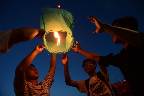   Several students fly a Kongming lantern to mourn the death of Wang Jialin and Ye Mengyuan, two young girls killed in a crash landing of an Asiana Airlines Boeing 777 at San Francisco airport, by the riverside in Jiangshan City, east China's Zhejiang Province, July 8, 2013. Local residents gathered at Xujiang Park in Jiangshan to show their grief to the 17-year-old Wang and 16-year-old Ye, who were students from Jiangshan High School. (Xinhua/Han Chuanhao)