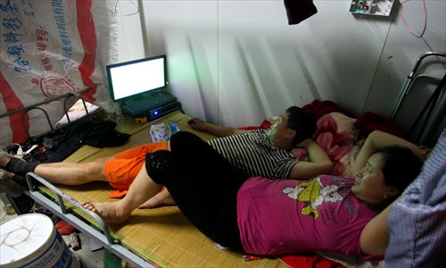 Henan native Ding, now a small labor contractor, plays computer games on a narrow bed while his wife watches closely.Photo: Yang Hui/GT
