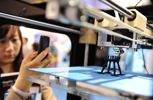 A visitor takes photos of a 3D printer which is working to print a chair model during the China (Shanghai) International Technology Fair in Shanghai, east China, May 8, 2013. (Xinhua/Lai Xinlin) 