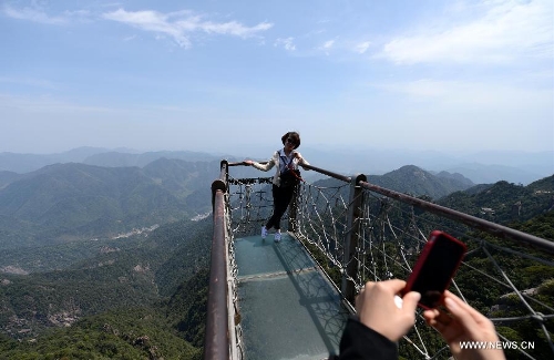 A tourist poses for photo in the Sanqing Mountain in east China's Jiangxi Province, April 13, 2013. The scenic area of Sanqing Mountain entered a peak tourist season as temperature rises recently. (Xinhua/Zhou Ke)&nbsp; 
