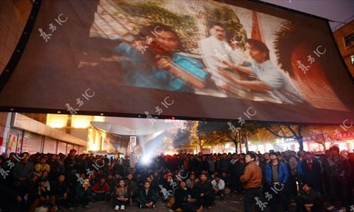 Migrant workers watch  a movie outside a job market in Yiwu, East China's Zhejiang Province on Sunday night. Since February 10, the eve of Chinese New Year, a movie projection team in Yiwu, a major manufacturing base, has shown films to migrant workers so they can have some entertainment  while spending the holiday away from their hometowns. Photo: IC