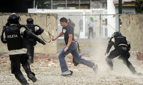 An opposition activist tries to escape from the national police during a protest against the government of Venezuelan President Nicolas Maduro, in Caracas on Monday. Two rival protests on Monday were the latest in an unresolved, nearly five-week-old crisis that has claimed lives of at least 20 people in the South American nation. Photo: AFP