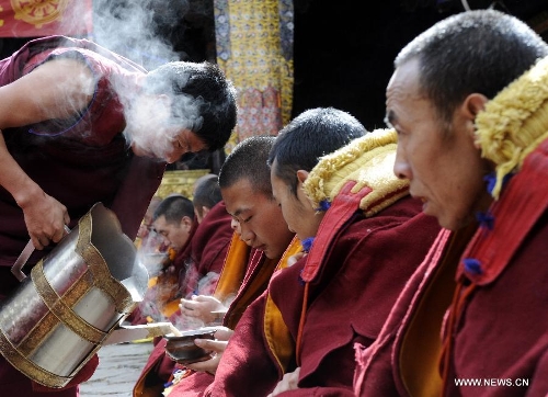 Drink is provided for monks at the ceremony of defending dissertations for Gexe Lharampa, the highest academic degree in Tibetan Buddhism studies, at the Jokhang Temple in Lhasa, capital of southwest China's Tibet Autonomous Region, April 5, 2013. Eight laureates of Gexe Lharampa were awarded here on Friday after they passed tests and defended their dissertations. Gexe means knowledgeable and Lharampa is the highest among the four ranks in the Gexe system. (Xinhua/Chogo)&nbsp; 
