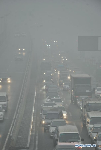 Motorcars run on a road amid fog and smog in Tianjin, north China, Feb. 28, 2013. The fog hit Tianjin on Feb. 28 morning, causing heavy air pollution in the city. (Xinhua/Yue Yuewei)