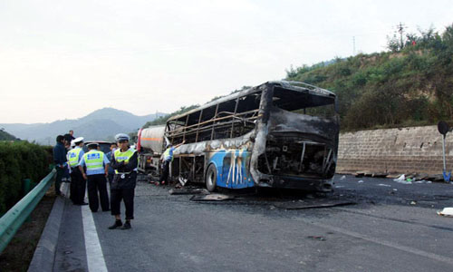 Traffic police work at the accident site after a collision between a 39-seat bus and a methanol-loaded tanker occurred in Yan'an City, northwest China's Shaanxi province, Aug. 26, 2012. The two vehicles caught fire after the collision in early Sunday morning, and at least 36 people were killed in the accident. Three people survived, but suffered injuries, said the local police. Photo: Xinhua