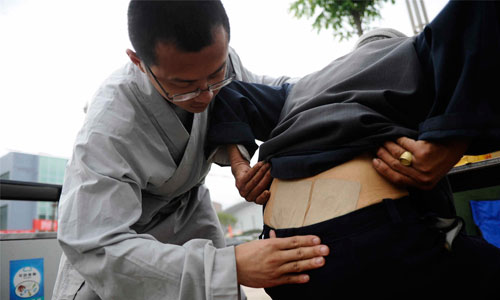 A Shaolin monk (left) treats a man injured during the Ya'an earthquake suffering from back pain on April 25. Monks from the famous Shaolin Temple in Henan Province visited quake-hit Lushan county to help treat those injured and distribute medicine. Photo: Li Hao/GT