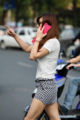 A young woman wearing summer suit walks on road in Nantong City, east China's Jiangsu Province, May 21, 2013. The highest temperature reached 31.9 degrees Celsius on Tuesday. (Xinhua/Xu Peiqin)