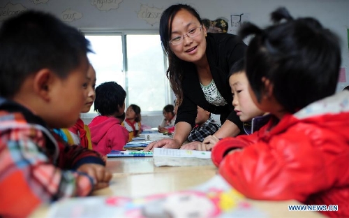 A teacher guides the students of the Hejiabao Central Primary School in reading during a trial class for the leapfrog education model in Dangchang County, northwest China's Gansu Province, May 27, 2013. The program, aimed at exploring a new education model and starting from 2011, has been carried out in 101 classes of 25 schools, covering about 4,000 students and 102 teachers. (Xinhua/Zhang Meng)