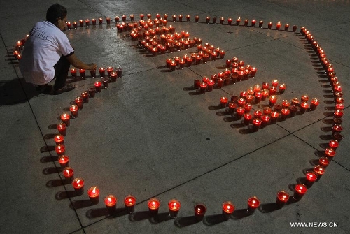 A woman lights candles during a commemoration event for the people that died on consequence of Human Immunodeficiency Virus (HIV), organized by the Atlacatl Association Vivo Positivo, at the Salvador del Mundo Square, in San Salvador, capital of El Salvador, on May 19, 2013. A total of 4,000 candles were lit during the event. (Xinhua/Oscar Rivera) 