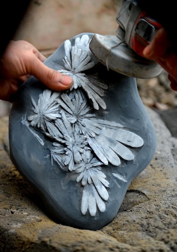 A craftsman named Qian Daishou polishes a semi-finished handicraft made of chrysanthemum stone in a workshop in Enshi, central China's Hubei Province, Jan. 12, 2013. 