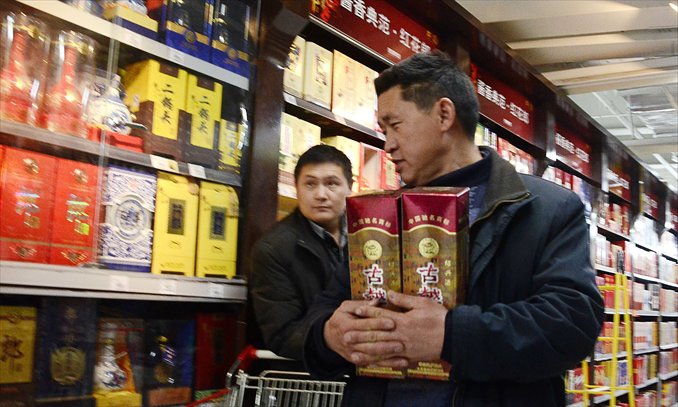 A man holds two bottles of baijiu as he walks in a supermarket in Beijing on Tuesday. The China Alcoholic Drinks Association said although all Chinese baijiu contained plasticizer, the amount is below the standard for the food industry. Photo: AFP