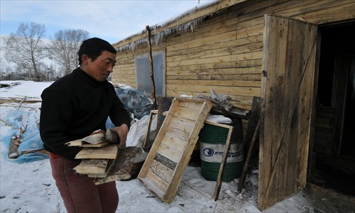 A Chinese man is carrying firewood to a dormitory where migrants from China live in Khakassia, Russia in February. Photo: CFP