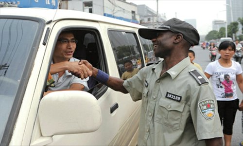 A foreign chengguan shakes hands warmly with a driver who has parked illegally and persuades him to move his car away.