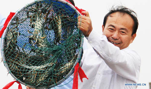 A man shows a net of newly-harvested Chinese mitten crabs of the Yangcheng Lake in Suzhou, east China's Jiangsu Province, September 22, 2012. The fishing and sale of Chinese mitten crabs of Yangcheng Lake this autumn was officially started on Saturday. Photo: Xinhua