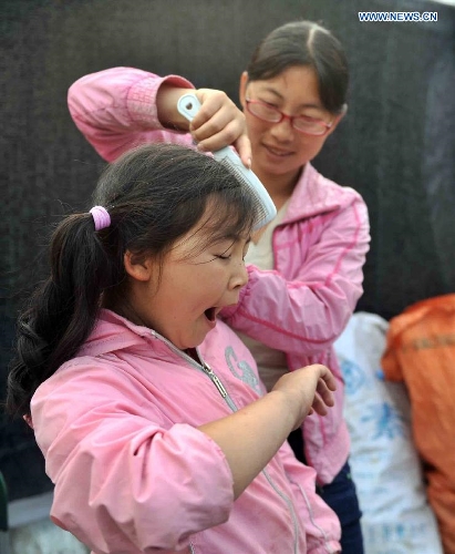 A mother combs hair for her daughter at a temporary settlement for quake-affected people in Lushan Middle School in Lushan County, southwest China's Sichuan Province, April 26, 2013. A 7.0-magnitude jolted Lushan County on April 20. (Xinhua/Li Wen)