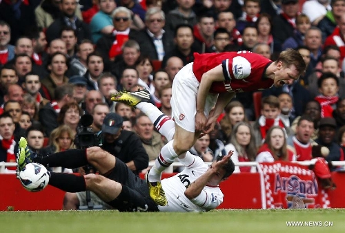 &nbsp;Robin van Persie (bottom) of Manchester United tackles Per Mertesacker of Arsenal during the Barclays Premier League match between Arsenal and Manchester United at the Emirates Stadium in London, Britain on April 28, 2013. The match ended with a 1-1 draw. (Xinhua/Wang Lili) 