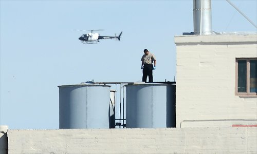 A worker stands on a water tank on the roof of the Hotel Cecil in Los Angeles California Wednesday. The body of 21-year-old Canadian tourist Elisa Lam was found in a water tank on the roof of the hotel three weeks after she went missing, police said. The corpse was found Tuesday after hotel guests complained of low water pressure. Photo: AFP
