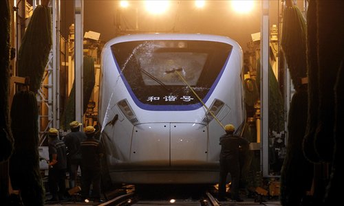 Workers clean the aerodynamically-designed windscreen on a bullet train. Photo: Yang Hui/GT