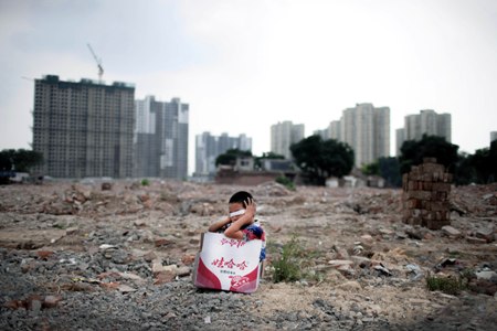 A child sits, covering his eyes in the rubble of mostly demolished Shiliuzhuang village, Fengtai district Monday. Photo: Li Hao/GT