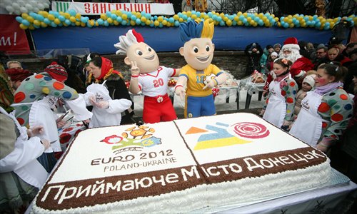Ukrainian cooks present a huge cake with the logo and mascots of Euro 2012 during a costume festival in Donetsk. Photo: IC