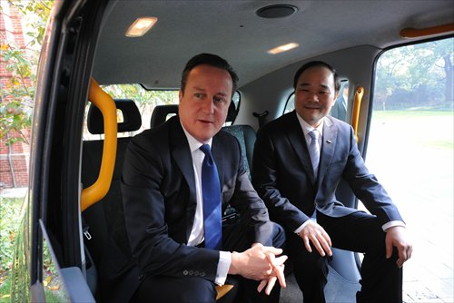 British Prime Minister David Cameron sits in a London-style black cab with Geely Chairman Li Shufu. Li intends to operate London-style taxis in Shanghai. Photo: CFP