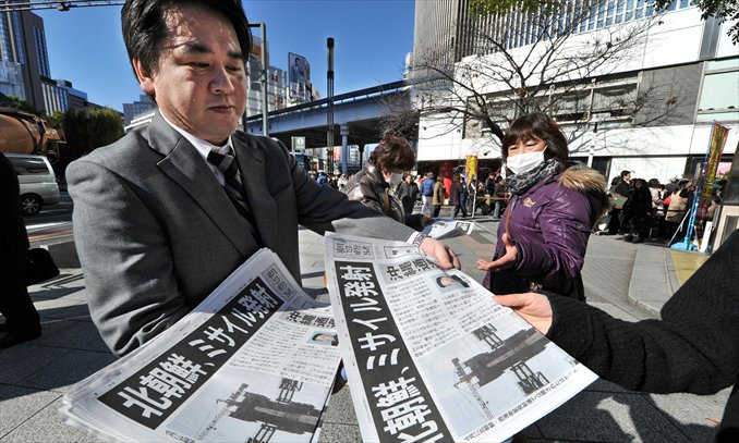 A worker from one of Japan's major newspapers hands out extra editions reporting a rocket launch by North Korea in downtown Tokyo on Wednesday. North Korea successfully put a satellite into orbit Wednesday in defiance of UN sanction threats over what Pyongyang's critics have condemned as a disguised ballistic missile test. Photo: AFP