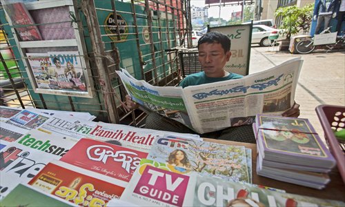 A street vendor reads a new private daily as he sells newspapers and weekly journals at a roadside stall in Yangon, Myanmar, on April 1, 2013. Myanmar ended a five-decade state monopoly on daily news, when four privately owned newspapers hit the streets. Photo: CFP